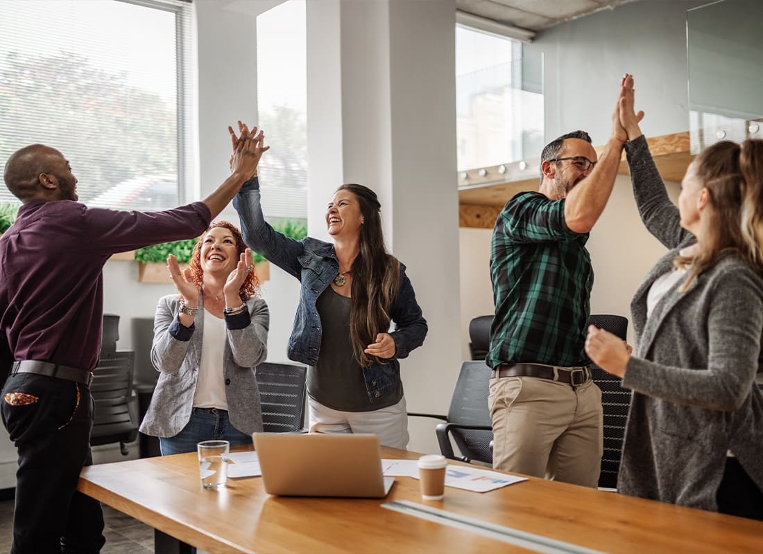 About Our Agency - An Office Team Celebrating Good Work by High Fiving Each Other in a Modern Office